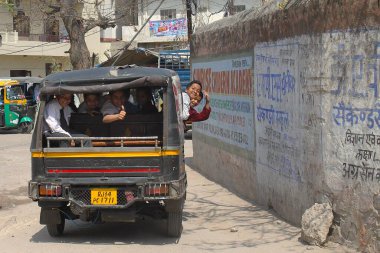 Jaipur, Rajasthan, Hindistan - 08 Mart 2019: Şehir merkezinde okul üniformalı arkadaşça el sallayan öğrencilerle dolu bir okul otobüsü gibi davranan sokak manzarası. Erkekler ve bir kız..
