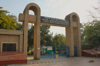 Agra, Uttar Pradesh, Hindistan - 11 Mart 2019: Ulusal JALMA Cüzzam ve Diğer Mycobakteriyel Hastalıklar Enstitüsü 'ne (NJILOMD) açık giriş kapısı, Hindistan Tıbbi Araştırma Konseyi. Başıboş köpek önde yatıyor..