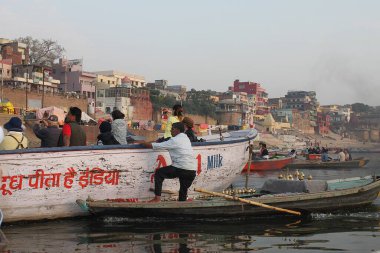 Varanasi, Uttar Pradesh, Hindistan - 13 Mart 2019: Yerel halk ünlü Ghat 'ları ziyaret eden ve onları Ganj nehrinin kıyısından izleyen turistler için tekne gezileriyle geçiniyor. 