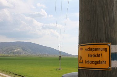 Marchegg, Gaenserndorf, Aşağı Avusturya - 05 Nisan 2025: Yüksek voltaj uyarısı olan elektrik direği! Elektrik sağlayıcısı Energie Versorgung Niedersterreich tarafından işletilen yaşam tehlikesi.