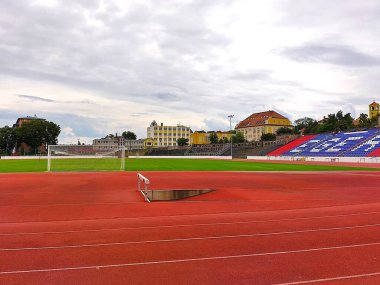 If, Heves, Macaristan, 5 Ağustos 2024: Szentmarjay Tibor Vrosi Stadyumu. Su sıçrayışlı koşu pisti ve gollü futbol sahası manzarası. Arkaplanda tarihi binalar.