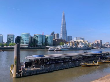 Londra, İngiltere, Birleşik Krallık - 08 Mayıs 2024: Thames nehri üzerinde demirli müze HMS Belfast ile City Cruises Pier ve şehir merkezinin ufuk çizgisi The Shard (eski Londra Köprüsü Kulesi)).