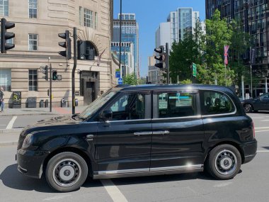 Londra, İngiltere, Birleşik Krallık - 08 Mayıs 2024: Hackney vagonu, şehir merkezindeki caddelerde yaygın bir manzara. Modern versiyon LEVC TX, Londra EV Company tarafından yapıldı. Tam-elektrik hibrit sürüş yağmuru.