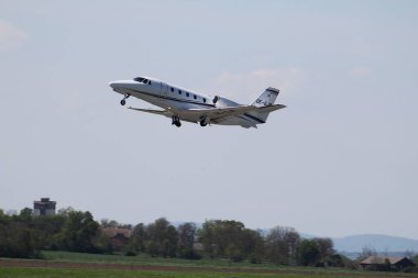 Schwechat, Aşağı Avusturya - 20 Nisan 2025: Avcon Jet OE-GJB Cessna Citation XLS + Viyana Uluslararası Havaalanı 16 nolu pistten kalkış sonrası iniş takımları.