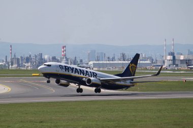 Schwechat, Aşağı Avusturya - 20 Nisan 2025: Uçak gemisi Ryanair SP-RKG Boeing 737-8AS Viyana Uluslararası Havaalanı 16 numaralı pistten havalanır. Sanayi tesisleri ve bulanık arka planda ufuk çizgisi.
