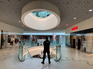 Viyana, Avusturya - 17 Nisan 2025: Bir güvenlik şirketinin çalışanı alışveriş merkezindeki merdivenlerin inişinde bacakları ayrık duruyor. Ceketinde Securiter yazıyor..
