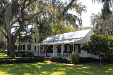 Bluffton, SC, ABD - 24 Eylül 2024: Low Country için tipik güzel evlerin manzarası. Ağaçlar ve İspanyol yosunları çerçevelemiş. Verandalı ve panjurlu güzel bir ev..