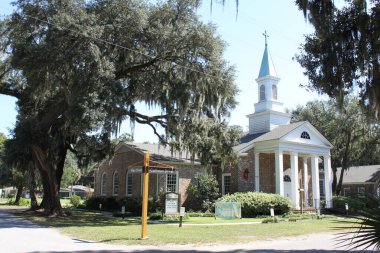 Bluffton, SC, ABD - 24 Eylül 2024: Birleşik Metodist Kilisesi (UMC) Güney Carolina 'nın Bluffton kıyı kasabasında. Meşe ağaçları ve İspanyol yosunları tarafından çerçevelenmiş. Düşler Ülkesi 'nde güneşli güzel bir gün. 