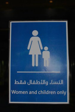 Dubai, Birleşik Arap Emirlikleri - Ekim 02, 2012: Sadece İngilizce ve Arapça dillerde kadın ve çocuklara erişimi kısıtlayan imzalar. Kadın ve çocuğun beyaz logosu. Dikey. Çubuk şekilli cinsiyet sembolleri.