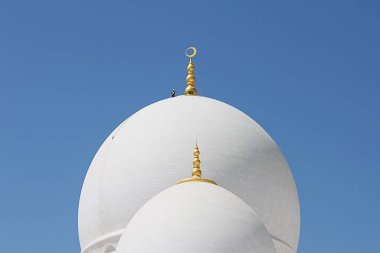 Abu Dabi, Birleşik Arap Emirlikleri - 07 Ekim 2012: Şeyh Zayed Ulu Camii 'nin devasa kubbelerinden birinde güvenlik halatı olan küçük bir işçi duruyor. Mavi gökyüzü beyaz bilyeyle çelişiyor.