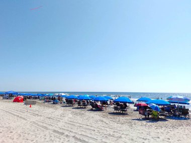 Hilton Head Adası, SC, ABD - 24 Eylül 2024: Lowcountry, Güney Carolina 'da güzel bir plaj sahnesi. Yazın Hilton Head Adası 'nda Coligny Beach Park' ta kalabalıktı. Mavi şemsiyeler, gökyüzünde uçurtma.