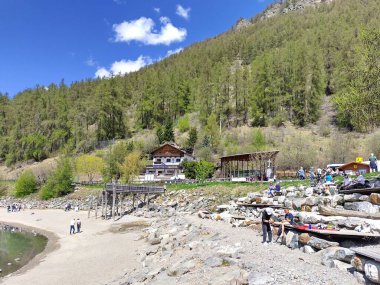Alt Graun (Vecchio Curon), Vinschgau, Trentino, Güney Tyrol, İtalya - 1 Mayıs 2025: Reschensee gölündeki turistler (Lago di Resia Gölü, Reschen). Batık kilisenin çan kulesini ziyaret ediyorum. Baharda güneşli bir gün.