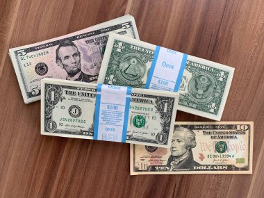 Viyana, Avusturya - 14 Mayıs 2025: Gıcır gıcır bir tomar Amerikan doları banknotunun yanı sıra beş ve on dolarlık banknotlar. BEP gravür ve baskı bürosu tarafından yeni üretildi. Ahşap arka planda $.