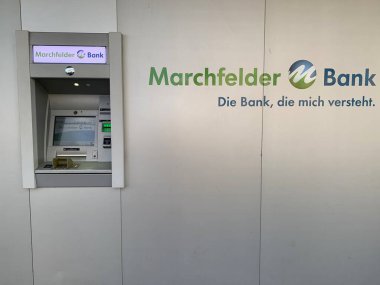Stratof, Gaenserndorf, Aşağı Avusturya - 15 Mayıs 2025: Otomatik veznedar ATM 'si kooperatif banka Marchfelder Bank şube binası önünde. Alman sloganı: Beni anlayan banka.