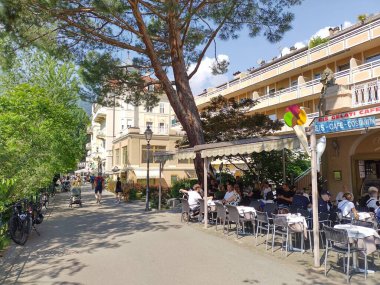 Meran, Trentino, Güney Tyrol, İtalya 1 Mayıs 2025: Merano 'daki Passer Nehri boyunca uzanan Kur Promenade' deki Gelateria 'nın (dondurma dükkanı) dış oturma alanı. Yürüyen insanlar. Güneşli gün, bahar. 