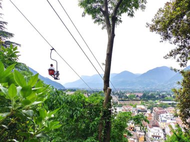 Meran, Güney Tyrol, İtalya 3 Mayıs 2025: Eski model teleferiğe binen adam yokuş aşağı. Panoramik kaldırma (Panoramalift) 1940 'lardan beri Merano kentini Tirolo (Dorf Tirol) köyüne bağlar. Baharda güneşli bir gün.