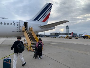 Schwechat, Aşağı Avusturya - 23 Mayıs 2025: Yolcular Air France Airbus A220-300 'e Viyana Uluslararası Havalimanı apronundaki mobil biniş merdivenlerinden geçerek biniyorlar. Belirgin kule binası. 