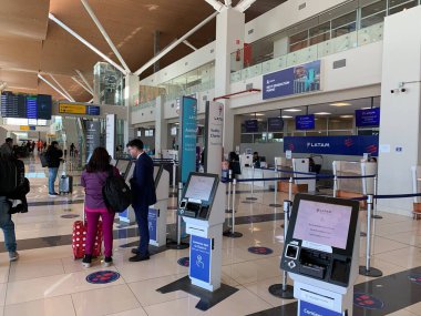 Calama, Antofagasta, Şili - Haziran 06, 2025: Modern El Loa Havaalanı SCCF 'de CUSS self-servis büfesi ile kontrol alanı. Yer ekibi yolcuyu destekliyor. Uçuş Bilgileri Görünüm Sistemi FIDS.