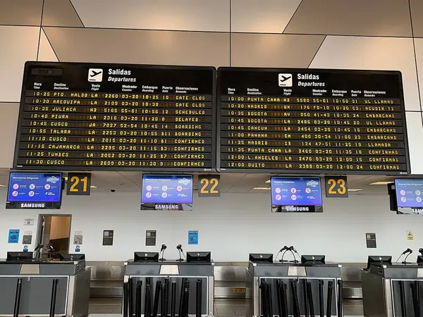 Callao, Lima, Peru - 25 Mayıs 2025: Jorge Chvez Uluslararası Havaalanı 'nın kalkış salonundaki bavulları kontrol edin. Arka planda Uçuş Bilgileri Görünüm Sistemi FIDS.