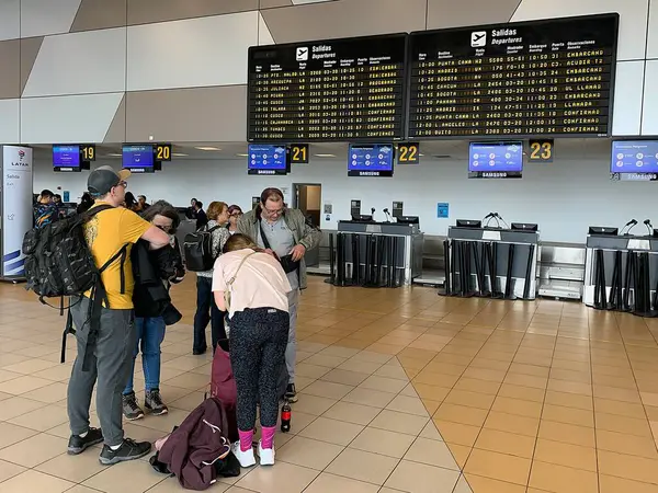 Callao, Lima, Peru - 25 Mayıs 2025: Yolcular Jorge Chvez Uluslararası Havalimanı 'nın kalkış salonundaki gişelerde bagajlarını kontrol ediyorlar. Arka planda Uçuş Bilgileri Görünüm Sistemi FIDS.