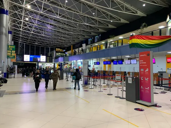 La Paz, Bolivya - 02 Haziran 2025: Yolcular El Alto Uluslararası Havaalanı SLLP 'nin kalkış salonundaki bavullarını kontrol ediyorlar. Renkli Bolivya bayrakları yolcuları karşılıyor.