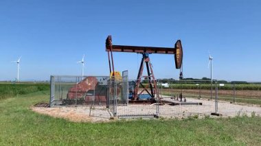 Eski paslı petrol pompası, yoğun olarak kullanılan verimli tarım arazileri, rüzgar türbinleri ve elektrik direkleri ile insanların etkisinde kaldığı kültürel bir yer..