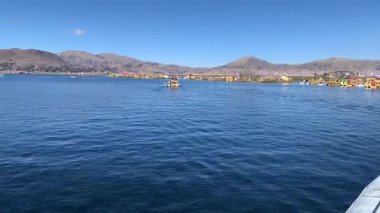 Puno, Peru - 29 Mayıs 2025: Titicaca Gölü 'ndeki feribot güvertesinden panoramik yuvarlak manzara yerli Uros adalarını birbirine bağlıyor. İki renkli Peru bayrağı sallıyor. 
