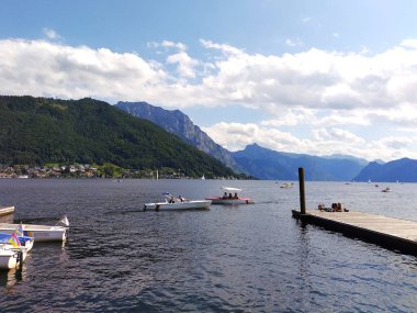 Gmunden, Avusturya 24 Ağustos 2025: Traunsee Gölü 'nden Gruenberg Dağı' na ve Traunstein Dağı 'na bir yaz günü manzara. Ön planda küçük elektrikli turist tekneleri. 