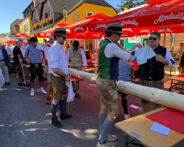 Viyana, Avusturya - 24 Ağustos 2025: Geleneksel giysiler içindeki güçlü gençler, geleneksel Viyana şarap üreticisi Neustifter Kirtag festivalinde sembolik Hiatabaum 'u (koruyucu ağaç) kaldırmaya hazırlanıyorlar.