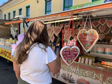 Viyana, Avusturya - 24 Ağustos 2025: Kadın, süslü zencefilli kek kalplerinin buzlu aşk metniyle süslendiği akıllı telefon kulübesinin fotoğrafını çekti. Aşk ve tatlıya düşkünlük.