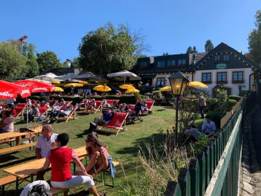 Viyana, Avusturya - 24 Ağustos 2025: Geleneksel Viyana şarap üreticisi festivali Neustifter Kirtag ziyaretçileri arka planda şarap tavernası Zeiler tarafından sunulan şezlonglarda dinleniyor. Eğimli arazi, sarı güneş gözlüğü.