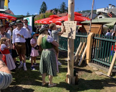Viyana, Avusturya - 24 Ağustos 2025: Geleneksel Viyana şarap üreticisi festivali Neustifter Kirtag sırasında ziyaretçiler sembolik Hiatabaum 'a (koruyucu ağaç) bir çivi çaktılar. Son çekiç darbesi kaybeder.