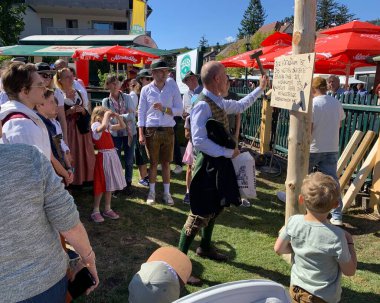 Viyana, Avusturya - 24 Ağustos 2025: Geleneksel Viyana şarap üreticisi festivali Neustifter Kirtag sırasında ziyaretçiler sembolik Hiatabaum 'a (koruyucu ağaç) bir çivi çaktılar. Son çekiç darbesi kaybeder.