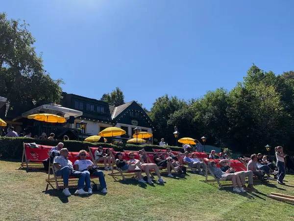 Viyana, Avusturya - 24 Ağustos 2025: Geleneksel Viyana şarap üreticisi festivali Neustifter Kirtag ziyaretçileri arka planda şarap tavernası Zeiler tarafından sunulan şezlonglarda dinleniyor. Eğimli arazi, sarı güneş gözlüğü.