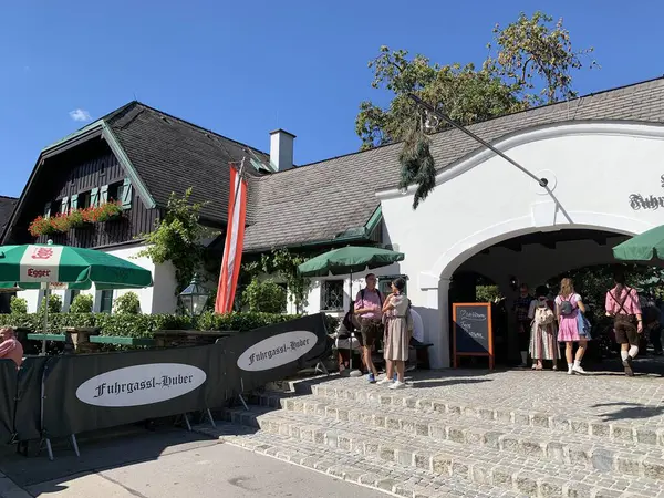 Viyana, Avusturya - 24 Ağustos 2025: Şarap tavernası Weingut Fuhrgassl-Huber 'a çam ağacından yapılmış giriş kapısı açık olduklarını gösteriyor. Geleneksel kıyafetler giyen ziyaretçiler. Ausg 'steckt!