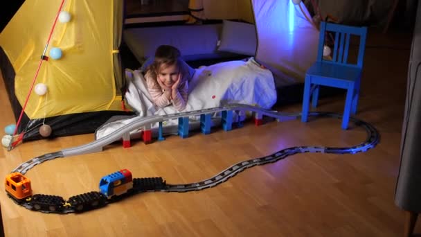 可爱的小女孩玩铁路 在帐篷里训练 有趣的幼儿小女孩玩玩具火车连接塑料轨道在地板上的家 可爱的孩子 高质量的4K镜头 — 图库视频影像