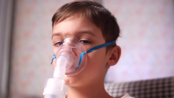 カメラを見ている男の子の肖像画を閉じます 小さな男の子は咳と気管支炎の間に吸入マスクで座っています 自宅で吸入器で ネブライザーで治療する 高品質の4K映像 — ストック動画
