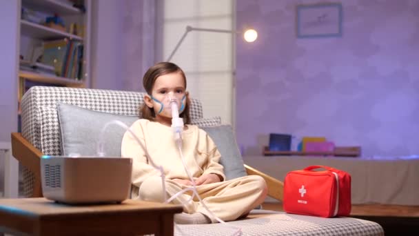 女孩看着相机 小女孩在咳嗽和支气管炎时 戴着吸入口罩坐在那里 在家里用吸入器雾化器治疗 高质量的4K镜头 — 图库视频影像
