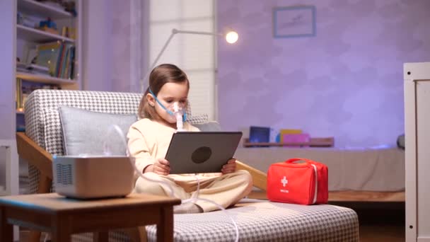 少年は 医療処置中にタブレットでビデオ演劇を見ています ネブラライザーマスク装置を使用して 子供の少年は家で吸入ネブラライザーの蒸気咳を作ります 保健医療について 4Kについて ホームトリートメント — ストック動画