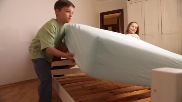 子供は父親を助けます 親は家事をする 父親および子供は新しいベッドを準備し マットレスを置き ベッドを作ります — ストック動画