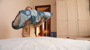 Küçük kız çarşafları değiştirip yatağı yapıyor. Çocuk ev işlerinde ebeveynlerine yardım eder. Çocuklar ev işlerini birlikte yaparlar..