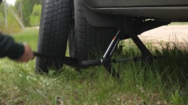 close-up timelapse of a jack lowering a car on the side of the road to change a tire. Car breakdown on the road. The driver himself changes a flat tire to a spare one.