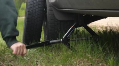 close-up of a jack lifting a car on the side of the road to change a tire. Car breakdown on the road. The driver himself changes a flat tire to a spare one.