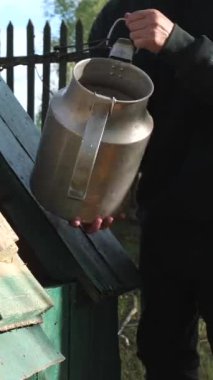 Bir adam eski bir köy kuyusundan el yapımı içme suyu alıyor. Bir adam kovayı kuyudan tatlı suyla doldurur.