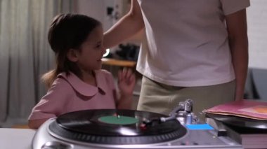 Anne ve kızı eski bir vinil pikaptan müzik eşliğinde dans ediyorlar. Anne ve küçük kız dans ediyor ve evde eğleniyorlar. Anne ve kızı birlikte vakit geçiriyorlar.
