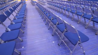 Seminerden, konserden, ön seçimlerden önce izleyicisi olmayan boş mavi sandalyeler. Geçici seyirci koltukları. Metal katlanır sandalyeler.