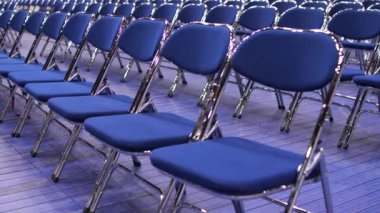 Seminerden, konserden, ön seçimlerden önce izleyicisi olmayan boş mavi sandalyelerin yakın çekimleri. Geçici seyirci koltukları. Metal katlanır sandalyeler. kamera hareketleri