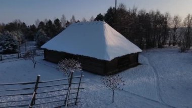 Köydeki eski ahşap bina. Karda sazdan çatılı bir ahır. Doğu Avrupa, Ukrayna ya da Belarus 'ta bir köy. Kışın şafak vakti köyde. İnsansız hava aracı videosu, hava görüntüsü