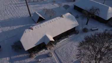 Eski bir Doğu Avrupa köyünde kışın şafak sökerken. Belarus 'ta bir köyde eski ahşap evler. İHA 'dan çekilmiş, hava manzaralı, yukarıdan. Kamera binadan yukarı uçuyor.