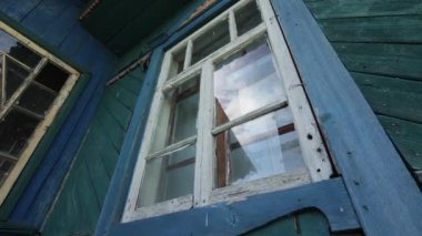 Ev yabani çalılarla kaplanmış. Terk edilmiş bir köy evinde kırık bir pencere. Köyde terk edilmiş ahşap bir evin penceresi..